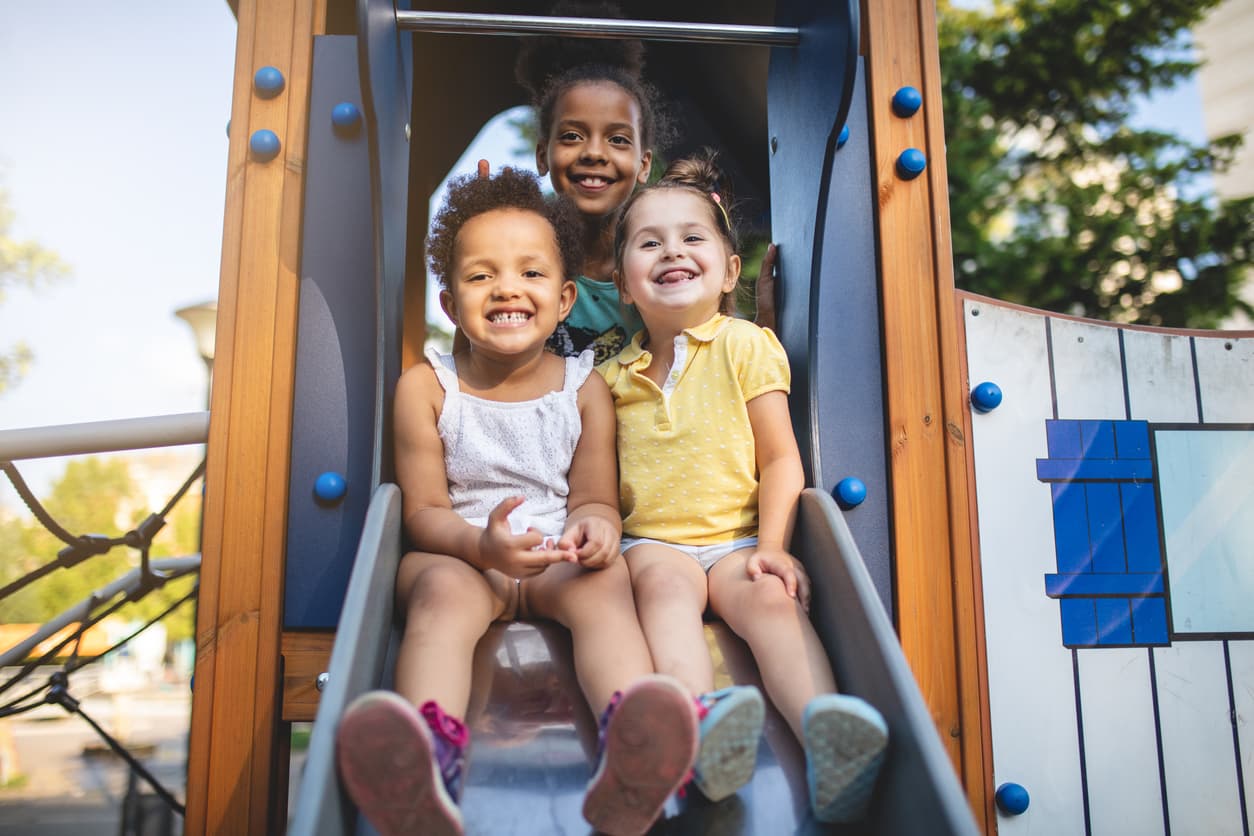 3 children smiling on the slide