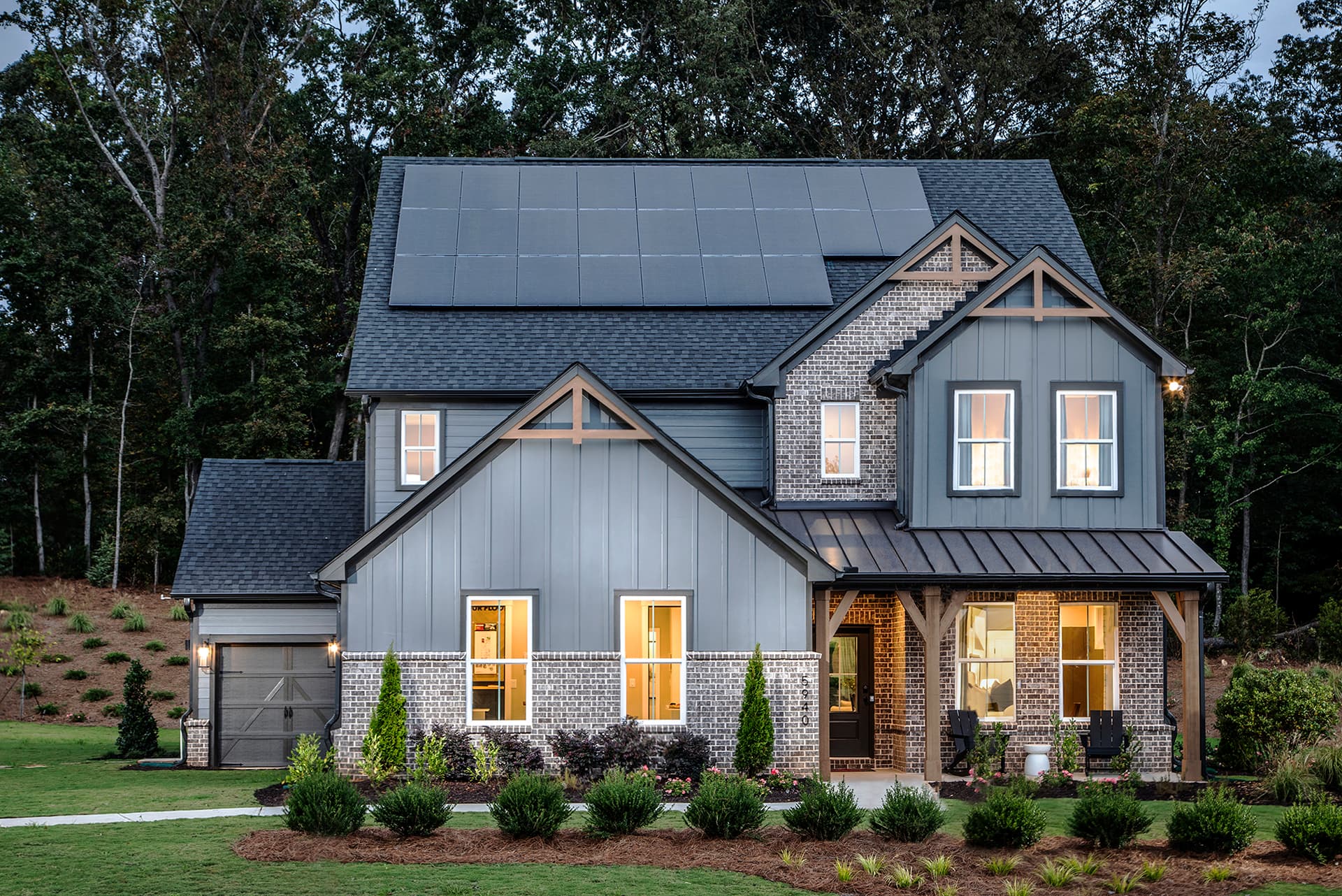 front of 2-story home with dark siding and brick